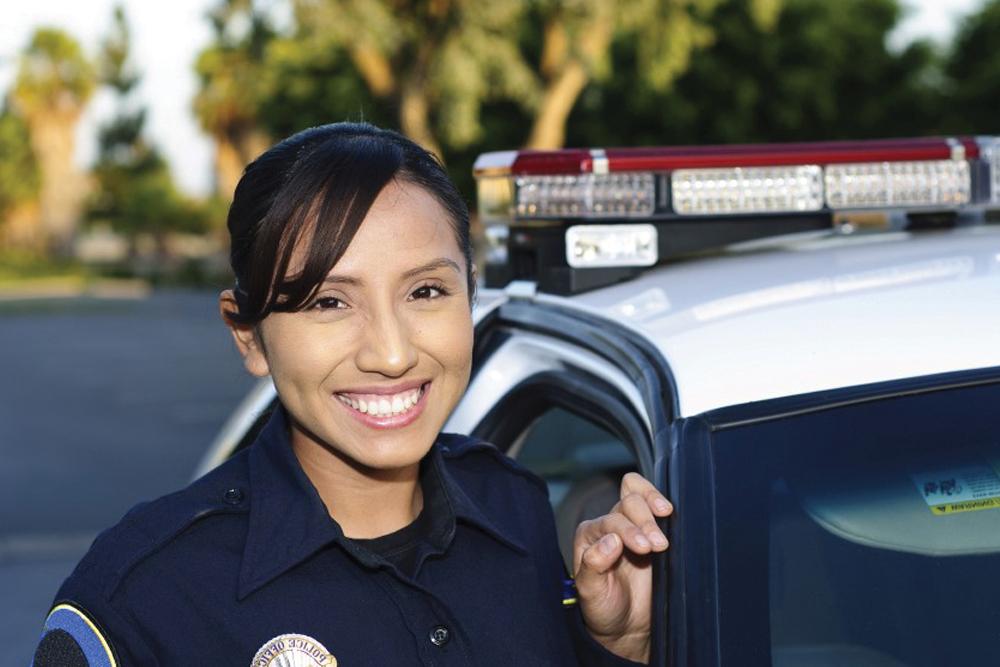 在警车旁微笑的刑事司法女警官